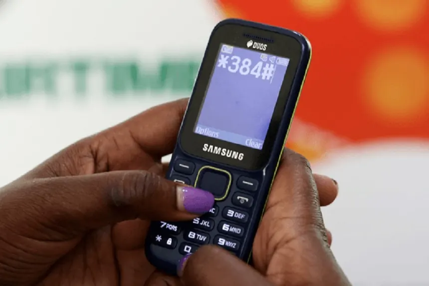 Hands dialing *384# on a Samsung basic phone with a physical keypad